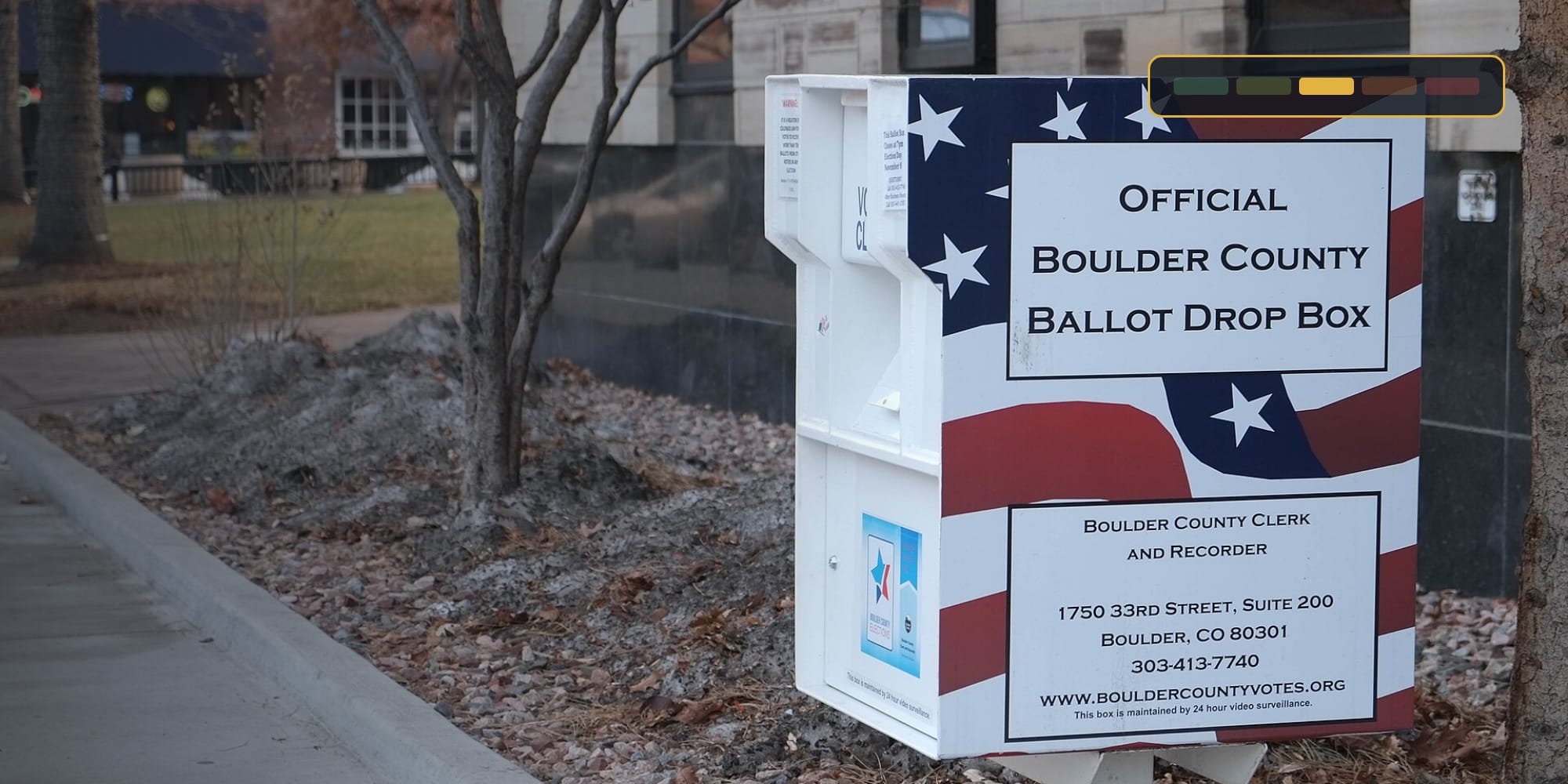 An official ballot drop box in Boulder County, Colorado, with the tracker's ELEVATED risk strip